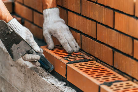 About 188890115 worker or mason hands laying bricks close up bricklayer works at brick row brickwork on
